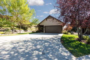 View of front facade featuring concrete driveway, stone siding, an attached garage, and a front yard