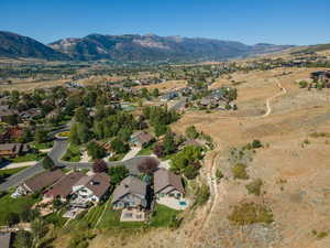 Aerial view of property and surrounding area with nearby suburban area and a mountainous background