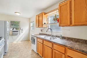 Kitchen featuring light tile patterned flooring, white appliances, dark countertops, brown cabinets, and cooling unit