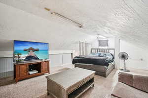 Bedroom featuring carpet, vaulted ceiling, and a textured ceiling