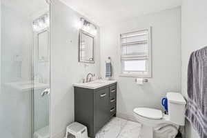 Full bath featuring a textured wall, vanity, a shower stall, and light marble finish flooring