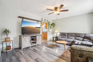 Living room with wood finished floors, a textured ceiling, and a ceiling fan