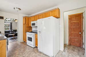 Kitchen featuring white appliances, brown cabinets, and dark countertops