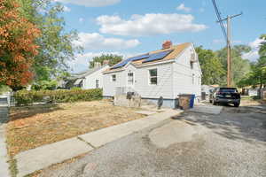 View of side of property featuring solar panels, a chimney, and roof with shingles
