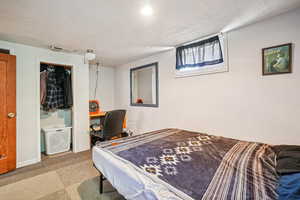 Carpeted bedroom with a textured ceiling, ensuite bath, and an office area