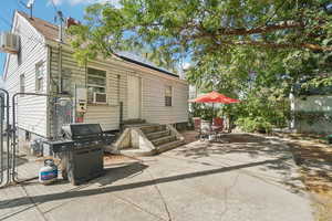 Back of property featuring a gate, a patio, roof mounted solar panels, and a wall unit AC