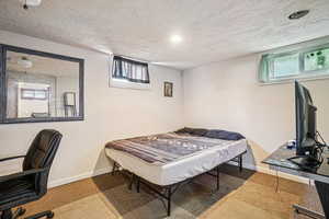 Carpeted bedroom with multiple windows, a textured ceiling, an office area, and recessed lighting