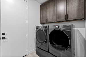 Washroom featuring cabinet space, independent washer and dryer, and light wood-style floors