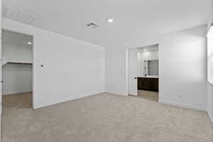 Unfurnished bedroom with light carpet, a walk in closet, recessed lighting, and connected bathroom