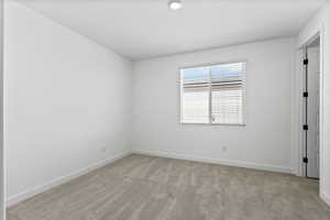 Empty room with light colored carpet and baseboards