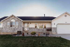 Ranch-style home featuring covered porch, a front yard, a garage, and brick siding