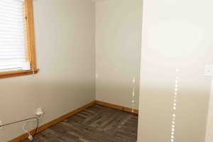 Spare/extra room with dark LVP wood-style flooring and baseboards