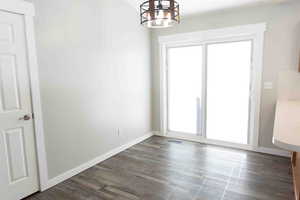 Dining area featuring a chandelier and dark LVP wood-style floors, double door to patio