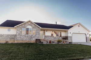 Ranch-style home with a front yard, covered porch, brick siding, and a garage