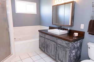 Master bathroom featuring vanity, a bath, and shower, light tile patterned flooring