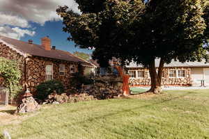 View from side of property, looking at back of home, garage and green lawn with a patio