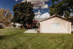 Rear view of garage & house featuring a patio/RV parking & yard