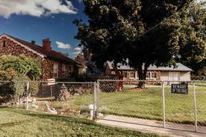 View of back facade & garage featuring a fenced front yard, stone siding, and a chimney