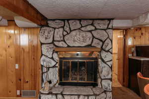 Family room with detailed view of wood walls, a fireplace, and a textured ceiling