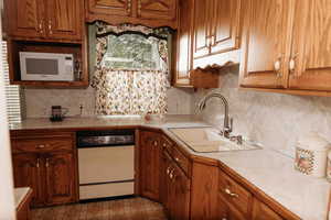 Kitchen featuring light countertops,oak cabinets, white appliances, and backsplash