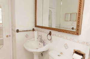 Bathroom with toilet, pedestal sink  and tile walls