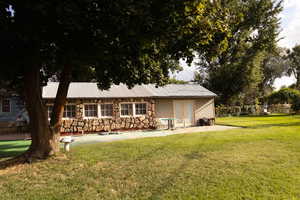 Side of garage featuring stone siding, a lawn, a patio area/RV parking