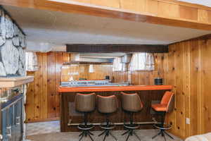 Indoor bar featuring sink, wooden walls, tile patterned floors, and a textured ceiling