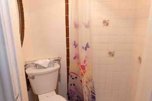 Bathroom featuring tile shower with curtain
