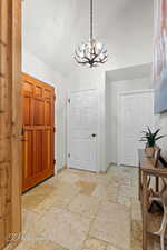Entryway featuring lofted ceiling, stone tile flooring, and a chandelier