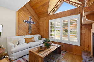Living area with wood walls, wood-type flooring, vaulted ceiling, and wooden ceiling