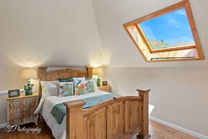 Bedroom featuring a skylight and light wood finished floors