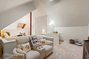 Living area featuring an upstairs landing, carpet flooring, and vaulted ceiling
