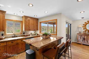 Kitchen with tasteful backsplash, brown cabinets, dishwasher, recessed lighting, and light wood finished floors