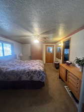 Bedroom featuring dark colored carpet, ceiling fan, and a textured ceiling