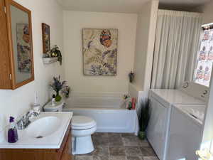 Bathroom with a bath, vanity, and washing machine and clothes dryer