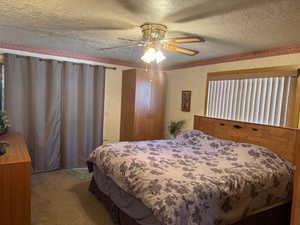 Bedroom featuring a textured ceiling, carpet flooring, wallpapered walls, and a ceiling fan