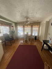 Dining area featuring wood finished floors, a textured ceiling, and ceiling fan