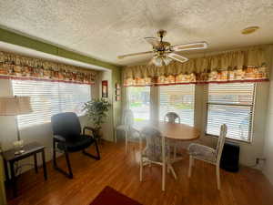 Dining room with a ceiling fan, wood finished floors, and a textured ceiling
