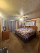 Carpeted bedroom featuring a textured ceiling and ceiling fan