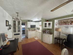 Kitchen featuring white cabinets, light wood-style floors, a chandelier, light countertops, and black appliances