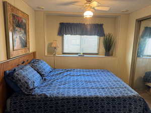 Bedroom featuring a textured ceiling, a ceiling fan, and wooden walls