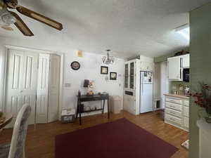 Kitchen featuring white cabinets, a textured ceiling, dark wood-type flooring, a chandelier, and light countertops