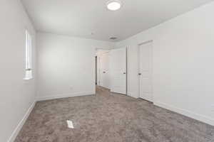 Unfurnished bedroom with light carpet and baseboards