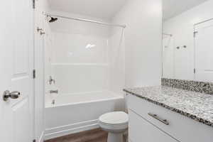 Bathroom with shower / bathtub combination, vanity, and dark wood-type flooring