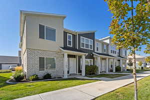 View of front of house featuring a residential view, board and batten siding, a front yard, brick siding, and covered porch
