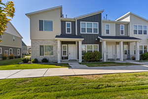 View of front of home with board and batten siding, a front yard, and brick siding