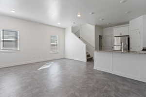 Unfurnished living room with stairs and recessed lighting