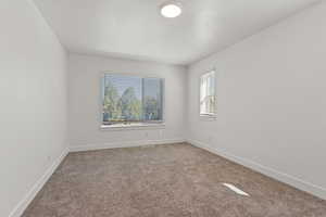 Unfurnished room featuring light carpet and baseboards