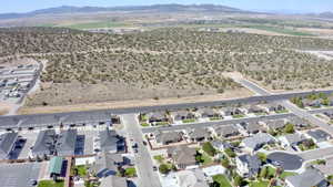Aerial view of property and surrounding area featuring a mountainous background and nearby suburban area