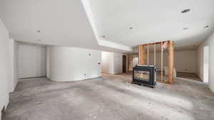 Unfurnished living room with a wood stove and unfinished concrete floors